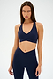 A person wearing a navy blue athletic outfit, featuring the SPLITS59 Mia Rigor Bra in Indigo, poses against a plain background.