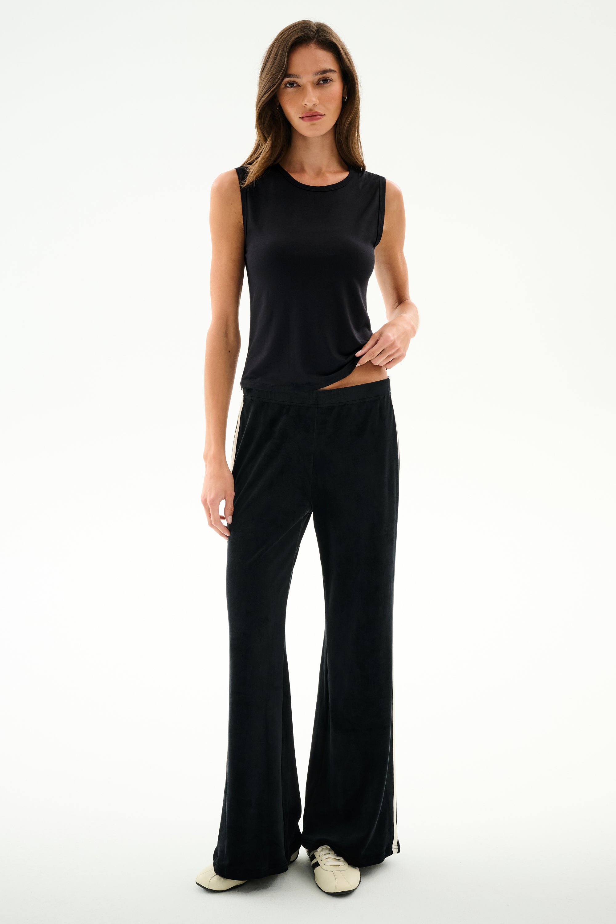 Woman standing against a white background, wearing the SPLITS59 Nikki Jersey Tank - Black, black wide-leg pants, and white shoes.
