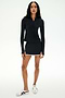 A person poses against a plain background in SPLITS59’s Ozzie Rigor Skort - Black/White, featuring built-in shorts and white trim, styled with a black long-sleeve top and white sneakers—ideal for court sports or everyday wear.
