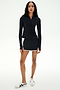 A person poses against a plain background in SPLITS59’s Ozzie Rigor Skort - Black/White, featuring built-in shorts and white trim, styled with a black long-sleeve top and white sneakers—ideal for court sports or everyday wear.