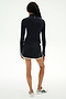 A person faces away, wearing a black long-sleeve top, SPLITS59 Ozzie Rigor Skort in Black/White—ideal for court sports—and white sneakers with black accents, set against a plain light background.