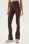A person wearing SPLITS59 Raquel High Waist Flared Legging in Dark Chocolate paired with white sneakers stands against a plain light background.
