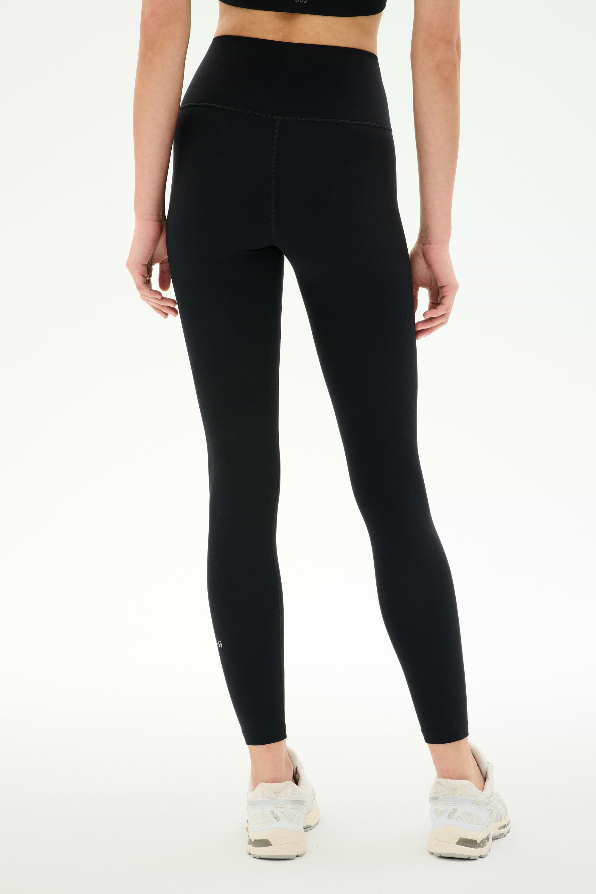 Model wearing SPLITS59 Airweight High Waist Legging in Black with white sneakers, shown from the back against a plain white background—ideal for hot yoga sessions.