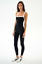 A woman wears the SPLITS59 Monah Rigor Jumpsuit 7/8 - Black/White and white sneakers, standing against a white background and looking neutrally at the camera.