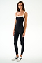 A woman wears the SPLITS59 Monah Rigor Jumpsuit 7/8 - Black/White and white sneakers, standing against a white background and looking neutrally at the camera.