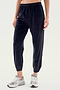 Person wearing black SPLITS59 Rhys Velour Jogger pants and gray sneakers, standing against a plain light background. Upper body is not visible, exemplifying effortless casual wear and ultimate comfort.
