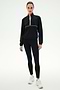 A person wearing the SPLITS59 Lyle Woven Nylon Pullover in Black/Creme, black spandex leggings, and white sneakers stands against a plain white background.