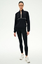 A person wearing the SPLITS59 Lyle Woven Nylon Pullover in Black/Creme, black spandex leggings, and white sneakers stands against a plain white background.