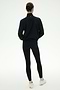 A person stands with their back to the camera, wearing the SPLITS59 Lyle Woven Nylon Pullover in Black/Creme, paired with black spandex leggings and white sneakers against a plain light background.