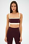 A woman faces forward against a white background, wearing the SPLITS59 Monah Rigor Bra in Dark Cherry/Creme with matching high-waisted leggings.