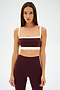 A woman faces forward against a white background, wearing the SPLITS59 Monah Rigor Bra in Dark Cherry/Creme with matching high-waisted leggings.