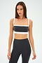 Poised against a plain backdrop, a person wearing a chic SPLITS59 Monah Rigor Bra in Graphite/White and black leggings is ready to conquer their gym workouts.