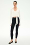 A woman wears the SPLITS59 Bella Airweight Lite Wrap in white, paired with black leggings and ballet flats, standing against a plain white background.