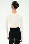 A woman with dark hair in a bun models the SPLITS59 Bella Airweight Lite Wrap in white, standing with her back to the camera against a plain white background.