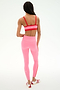 A person stands facing away, wearing SPLITS59's Clare High Waist Rigor 7/8 leggings in Strawberry/Lotus Red with a matching sports bra and white/red athletic shoes—perfect gym attire against a plain white background.
