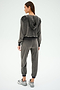 A woman in a Rhys Velour Zip Up Hoodie - Graphite by SPLITS59 stands with her back to the camera against a plain backdrop, showcasing comfort and versatility.