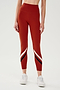 Front view of girl wearing red leggings with two white and black stripes across the shin white shoes
