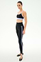 A woman models the SPLITS59 Ella High Waist Airweight 7/8 leggings in Black/Purple Haze with side stripes, paired with a black sports bra and black ballet flats, against a plain white background.