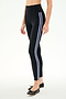 A person wears SPLITS59 Ella High Waist Airweight 7/8 leggings in Black/Purple Haze, featuring two light blue side stripes, paired with black ballet flats, standing against a plain white background.
