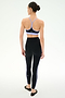 A woman faces away, wearing the SPLITS59 Ella High Waist Airweight 7/8 leggings in Black/Purple Haze with a lilac sports bra and black ballet flats.