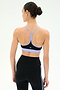 A woman faces away, hair in a bun, wearing the SPLITS59 Emerson Airweight Bra in Black/Purple Haze with high-waisted black leggings featuring a stripe detail.