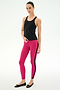 A woman poses against a plain background in the SPLITS59 Mel Airweight Lite Tank in black, paired with bright pink leggings featuring a black stripe—ideal for Pilates—and black ballet flats.