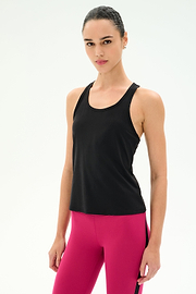 A person stands against a plain background wearing the SPLITS59 Mel Airweight Lite Tank in black and bright pink leggings—an ideal Pilates or hot yoga outfit—looking directly at the camera.
