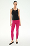 A woman faces forward in a SPLITS59 Mel Airweight Lite Tank - Black, paired with bright pink leggings featuring a black side stripe and black flats, standing against a plain white background—ideal for Pilates or hot yoga.