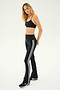 A woman with long blonde hair is wearing a black sports bra, the SPLITS59 Raquel High Waist Flared Legging in Black/White, and black sneakers. She stands facing slightly to the side against a plain background.