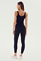 A woman standing and facing away, wearing a black sports tank top, Sprint High Waist Rigor 7/8 from SPLITS59 perfect for gym workouts, and white sneakers.