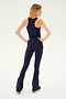 A woman stands with her back to the camera, hands on hips, wearing the SPLITS59 Kiki Rib Crop Tank in Indigo and navy blue high-waisted flare pants.