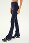 A person wearing SPLITS59's Raquel High Waist Flared Legging in indigo and athletic shoes stands against a plain background.