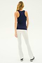 A person with long hair is standing, facing away from the camera. They are wearing the Kiki Rib Tank Full Length - Indigo from SPLITS59, white pants, and black and white sneakers—perfect attire for yoga or gym workouts. The background is plain and light-colored.