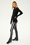 A person stands against a plain background, wearing a black long-sleeve top and SPLITS59's Raquel High Waist Flared Legging in Heather Grey with white and black stripes down the sides. The high waist leggings showcase their form perfectly, while their black and white sneakers complete the look.