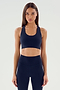 A person with long hair, dressed in an indigo Sara Airweight Bra by SPLITS59 and black leggings, stands poised against a plain light background, ready for a session of hot yoga or Pilates.