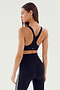 A woman with long hair is seen from behind, wearing the SPLITS59 Ella Airweight Bra in Black/White and airweight leggings with side stripes, perfect for hot yoga sessions.