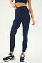 A person wearing a navy blue sports bra, SPLITS59's Airweight Super High Waist 7/8 leggings in Indigo, and black running shoes is standing against a plain background. The focus is on their lower body and apparel.