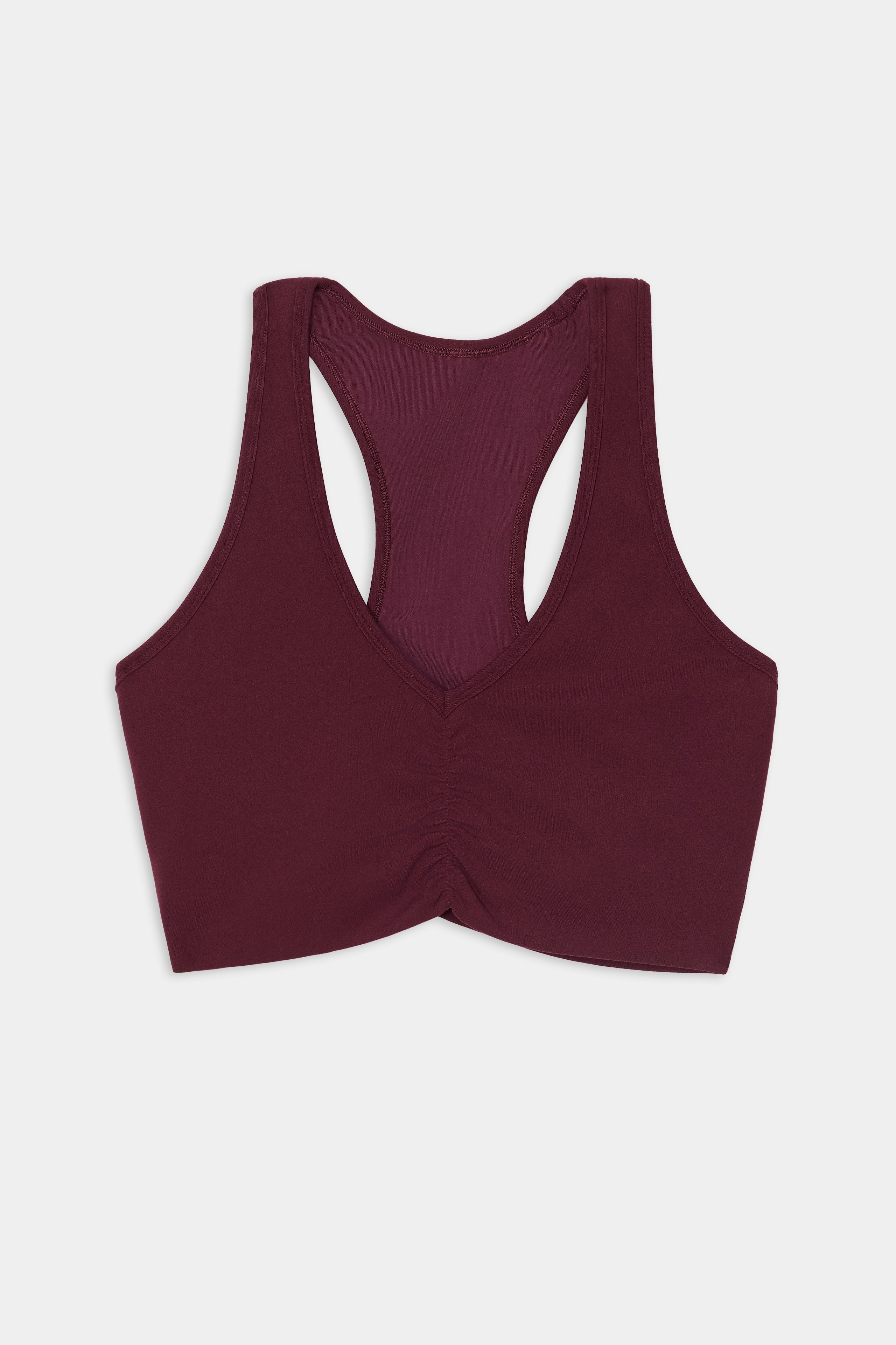 The SPLITS59 Airweight Bra With Ruching in Dark Cherry, featuring a ruched front and crafted from a soft nylon and spandex blend, is displayed flat on a white background.