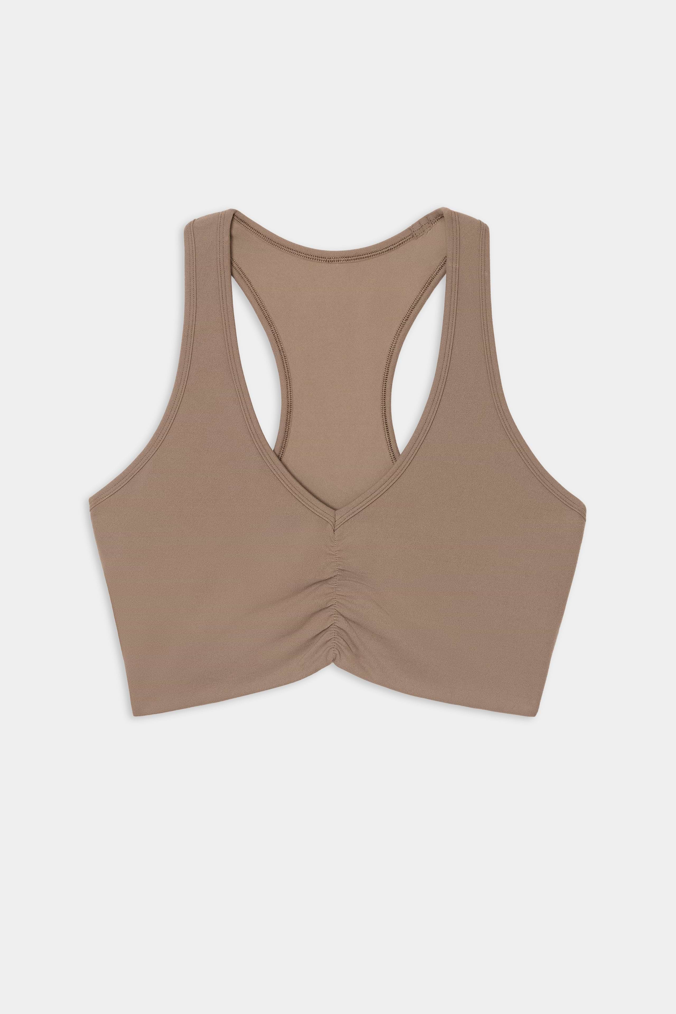 The SPLITS59 Airweight Bra With Ruching in Lentil is a beige racerback sports bra featuring ruched detailing at the front, crafted from a soft nylon and spandex blend, and displayed on a plain white background.