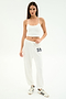 A woman wears the SPLITS59 Airweight Crop - White with white sweatpants featuring 59 and white Adidas sneakers, standing against a plain white background.