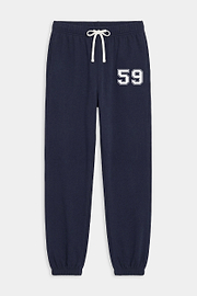 The SPLITS59 Andie Oversized Fleece Varsity 59 Sweatpant in Indigo features elastic cuffs, a white drawstring, side pockets, and "59" on the left thigh. Made in Los Angeles.