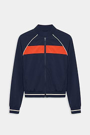 The SPLITS59 Carrie Woven Nylon Jacket in Indigo/Lotus Red features a zip-up design with a bright red chest stripe and white piping on the shoulders and cuffs, crafted from spandex and nylon.