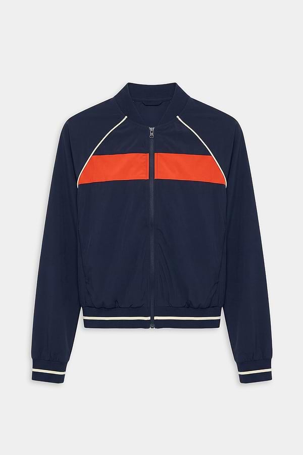 The SPLITS59 Carrie Woven Nylon Jacket in Indigo/Lotus Red features a zip-up design with a bright red chest stripe and white piping on the shoulders and cuffs, crafted from spandex and nylon.