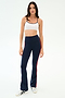 A woman faces forward against a plain background, wearing SPLITS59's Raquel High Waist Flared Legging in Indigo/Lotus Red and a white sports bra with white sneakers.