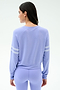 A woman with long dark hair wears the SPLITS59 Brooks Stripe Fleece Sweatshirt in Purple Haze/White, featuring two white sleeve stripes, made in Los Angeles, standing with her back to the camera.