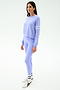 A woman faces slightly left, wearing the SPLITS59 Brooks Stripe Fleece Sweatshirt in Purple Haze/White with matching leggings, white socks, and sneakers against a plain light background.
