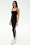 A woman stands against a plain background wearing the SPLITS59 Monah Rigor Tank in black, paired with black leggings featuring white side stripes, along with white socks and sneakers—ideal for gym workouts.