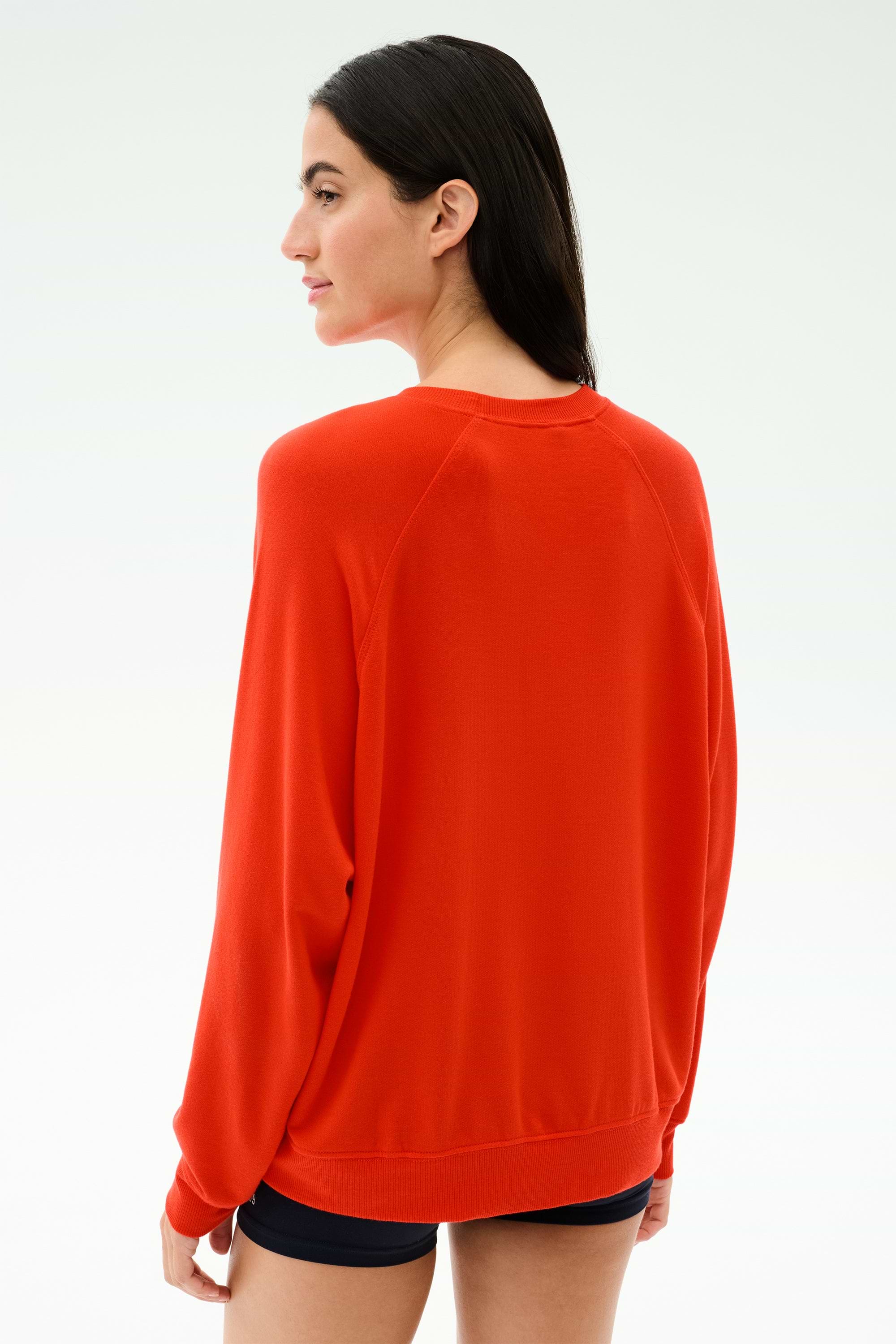 A person with long dark hair, seen from behind against a plain light background, wears the SPLITS59 Andie Oversized Fleece Sweatshirt in Lotus Red.