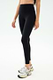 A person wears SPLITS59 Sprint High Waist Rigor 7/8 leggings in black with white athletic shoes, standing against a plain light background.