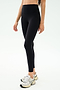 A person wears SPLITS59 Sprint High Waist Rigor 7/8 leggings in black with white athletic shoes, standing against a plain light background.